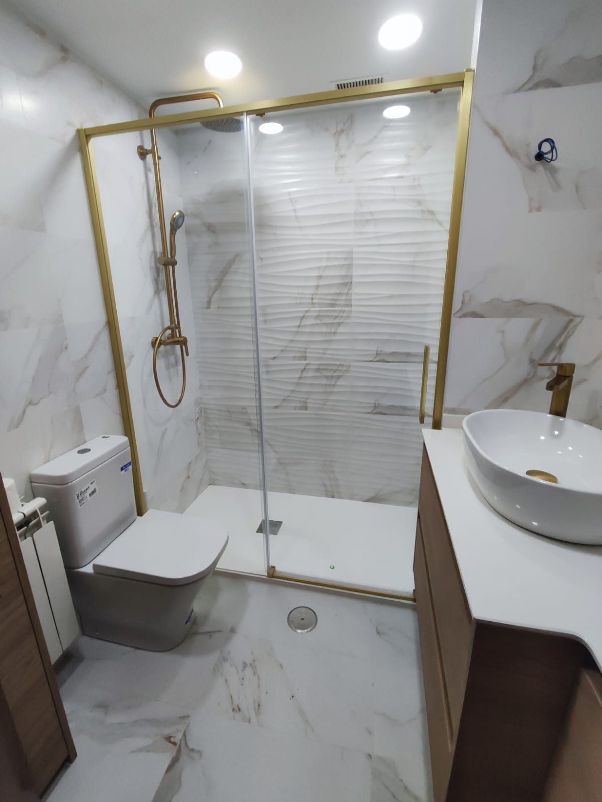 Baño después de la reforma con ducha y detalles dorados