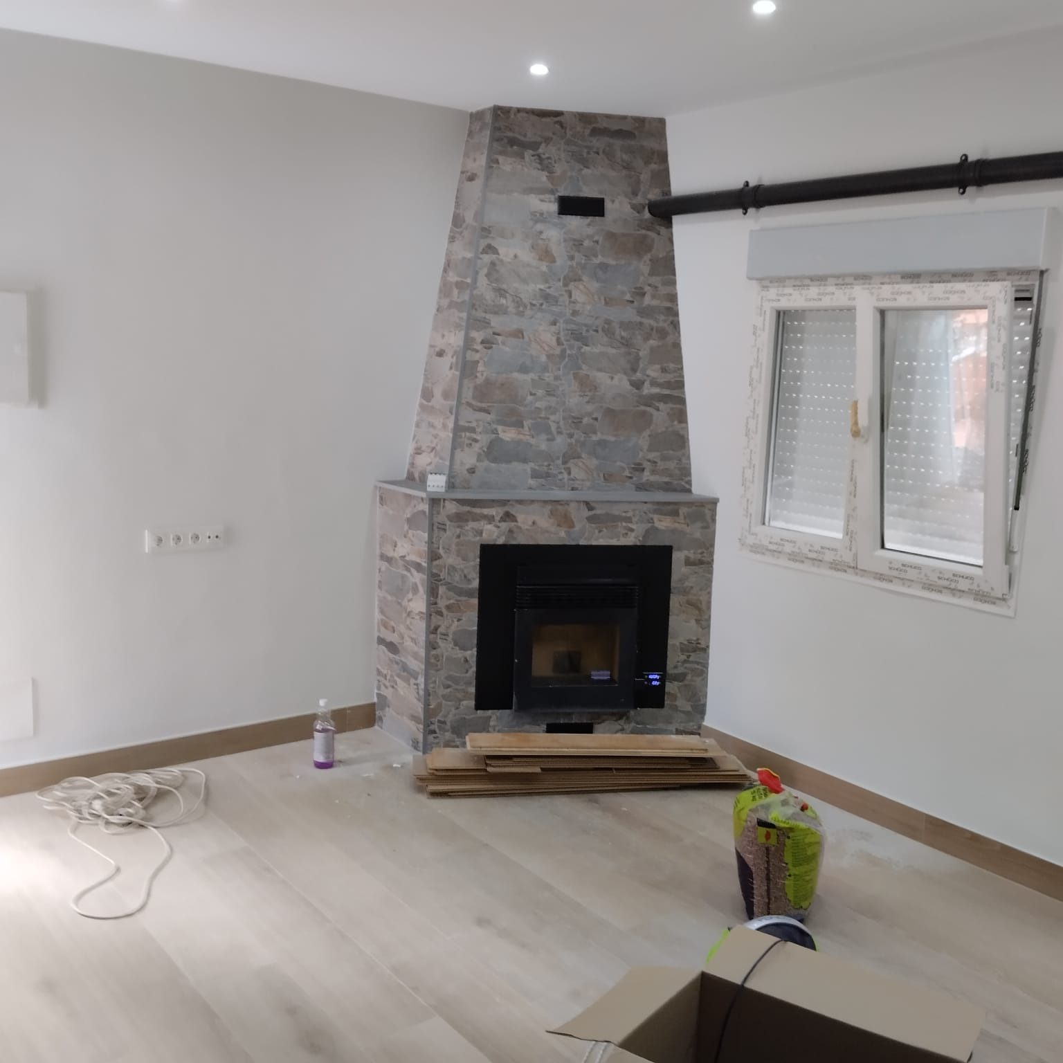 Salón con chimenea de piedra tras la reforma