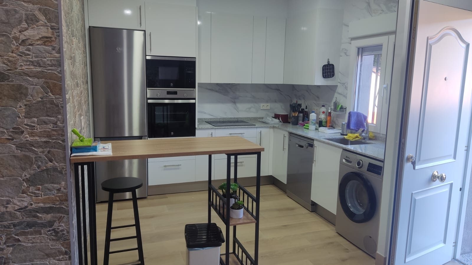 Cocina reformada con pared de piedra y barra